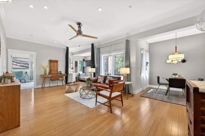 Open-concept living space featuring wood-finish flooring, recessed lighting, and crown molding