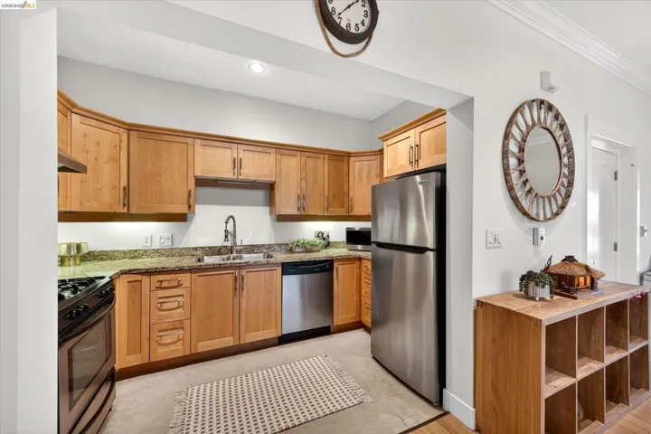 Kitchen featuring natural wood cabinetry, granite countertops, stainless steel appliances, and wood-finish flooring