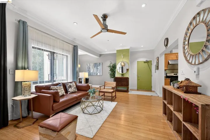 Hardwood-style flooring throughout the main living area, featuring a modern ceiling fan, crown molding, and a lime green accent wall