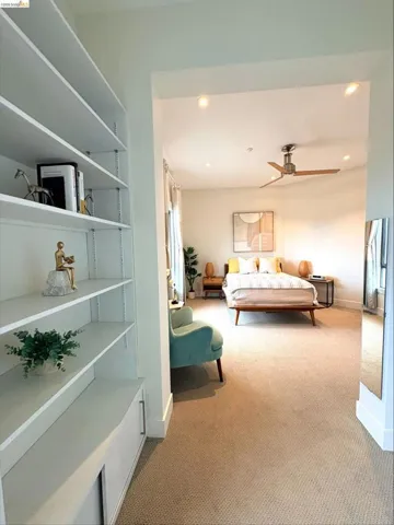 Recessed lighting illuminating a bedroom with a ceiling fan, carpeted flooring, and a built-in shelving unit with lower cabinetry