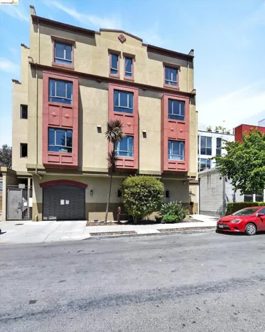 Multi-story building featuring a neutral-toned facade with pronounced red-orange window bay surrounds
