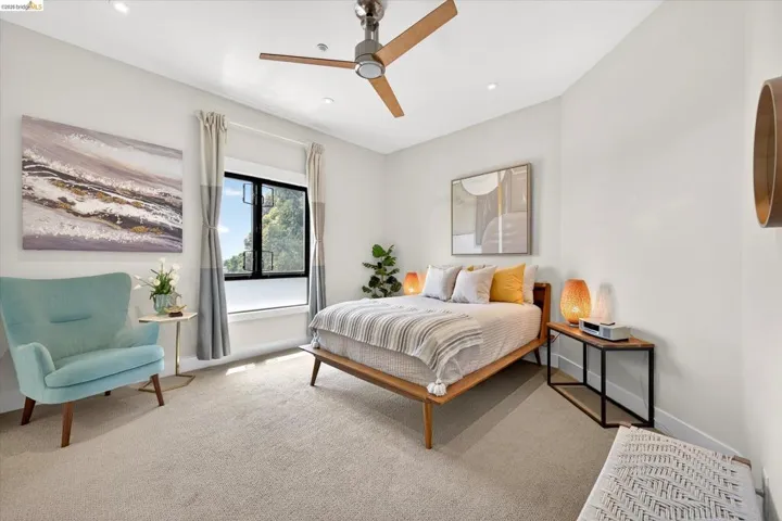 Carpeted room featuring a modern ceiling fan with wood-finish blades, recessed lighting, and a large window with dark trim