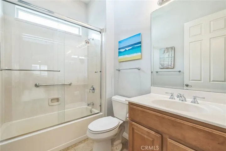Guest bathroom has a shower over the tub with glass enclosure.