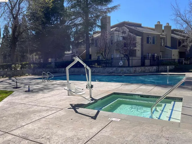 Swimming pool area featuring a spa, pool lift, and textured concrete decking