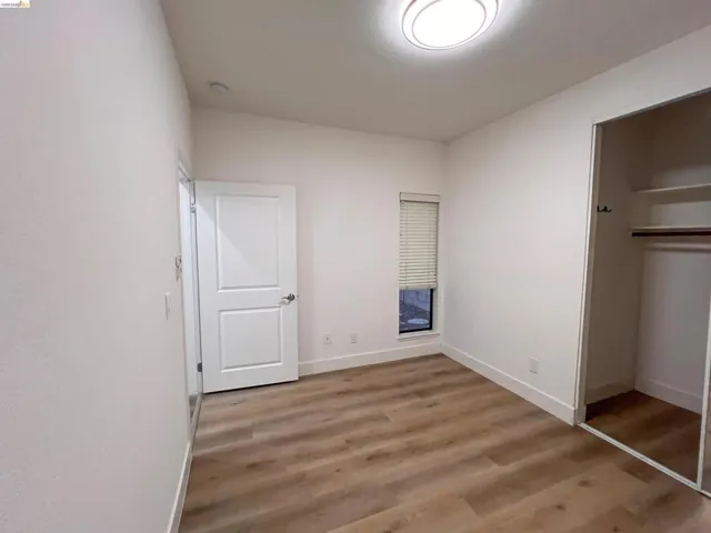 Room featuring wood-finish flooring, white walls, and a modern ceiling light fixture