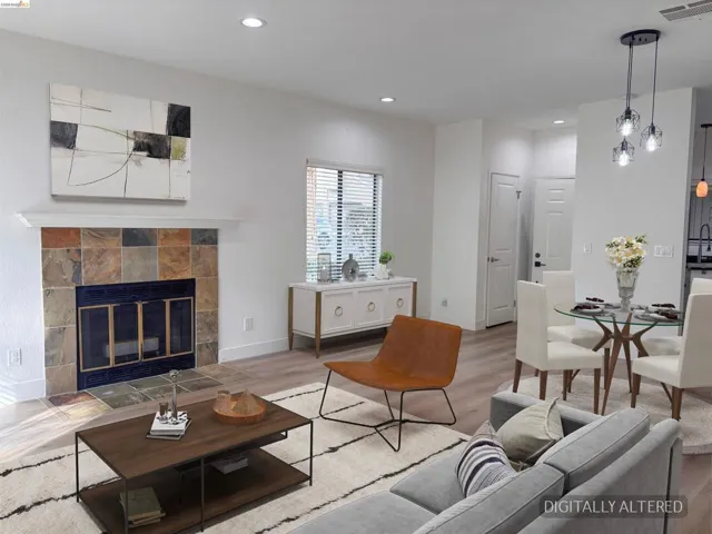 Open-concept living space featuring wood-finish flooring, recessed lighting, and a stone-tiled fireplace with a white mantel