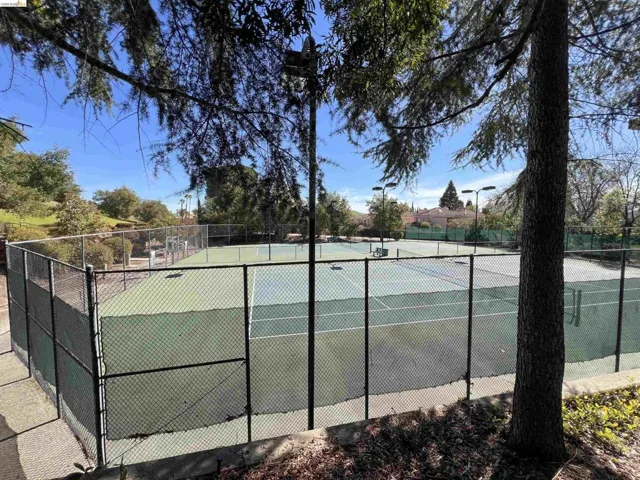 Tennis courts featuring chain-link fencing, a hard court surface, and court lighting