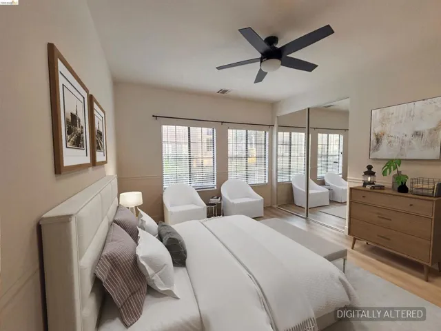 Spacious room featuring multiple windows with horizontal blinds, overhead ceiling fan with lighting, mirror-fronted sliding closet doors, and light wood-finish flooring