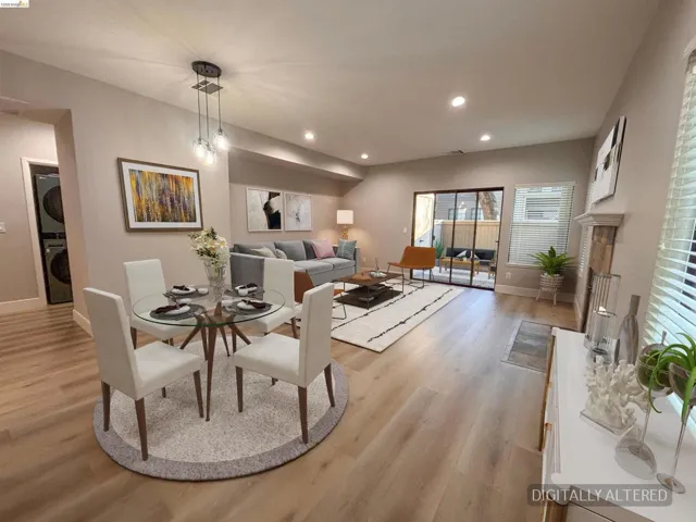Open-concept living area with wood-finish flooring, recessed lighting, and a modern fireplace with a stone surround