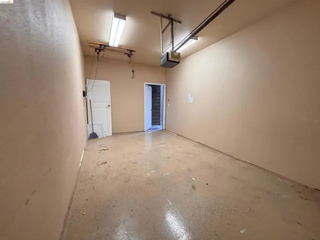 Spacious garage featuring a durable concrete floor, an overhead garage door opener, and fluorescent ceiling lighting