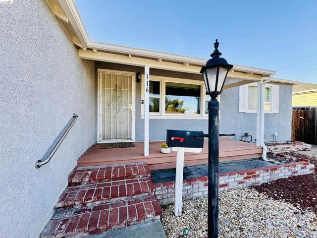 Front porch entry with a security screen door, red brick steps, and an exterior wall-mounted handrail