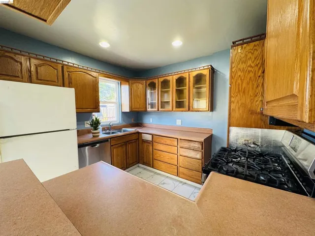 Kitchen featuring wood-finish cabinetry, a gas range, a double basin sink, and a dishwasher
