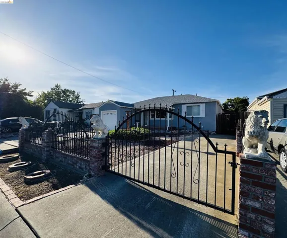 Gated property entrance featuring a wrought iron gate with decorative accents, brick columns, and stone lion sculptures
