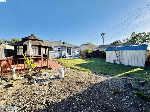 Backyard featuring a covered gazebo on a wood deck, a storage shed, and a grassy lawn area