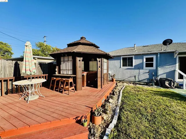 Expansive wood-finish deck featuring a built-in gazebo with a shingled roof, integrated bar seating, and privacy panels
