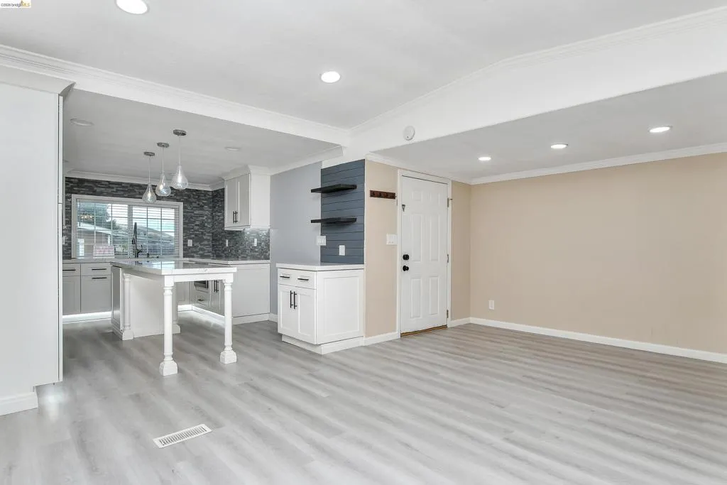 Kitchen with white cabinetry, open shelves, crown molding, backsplash, and light wood-style floors