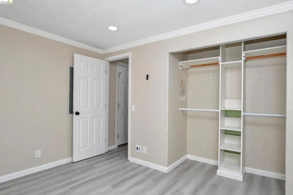Unfurnished bedroom with a closet, crown molding, light wood-style floors, and recessed lighting