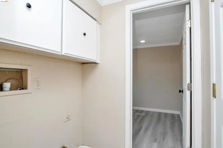 Laundry area featuring ornamental molding, light wood-style flooring, and cabinet space