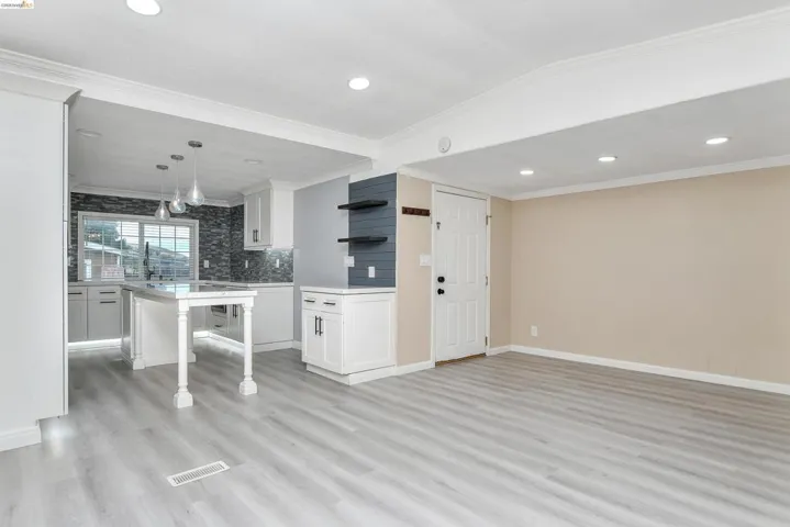 Kitchen with white cabinetry, open shelves, crown molding, backsplash, and light wood-style floors
