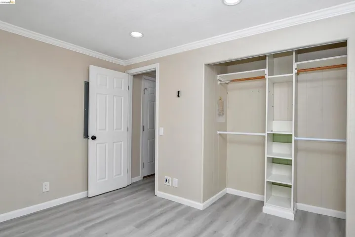 Unfurnished bedroom with a closet, crown molding, light wood-style floors, and recessed lighting