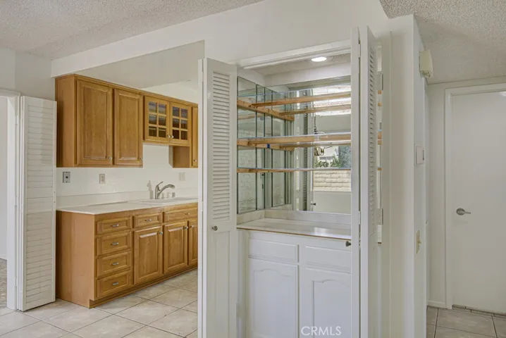 Cabinet storage and glass shelving just outside the kitchen.