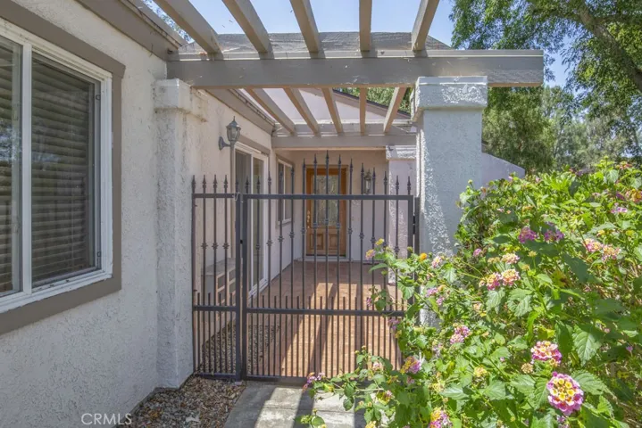Wrought-iron front gate open to a large courtyard.