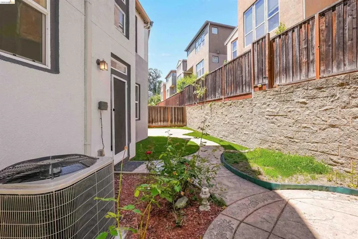 Private yard featuring a stamped concrete pathway, manicured lawn, and mature planter beds