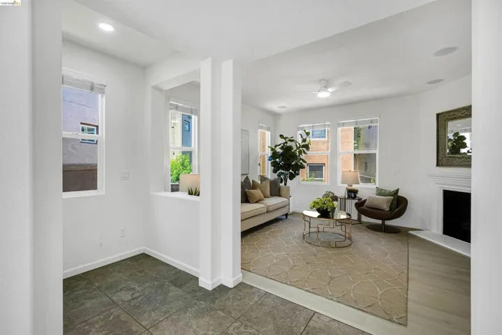 Living space featuring recessed lighting, multiple windows, a ceiling fan, a fireplace with a mantel, and light wood-finish flooring
