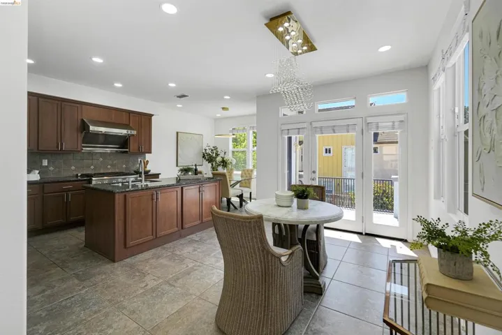 Open concept kitchen featuring dark wood cabinetry, a central island with a sink, stainless steel appliances, and tile flooring