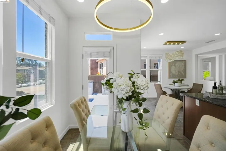 Bright dining area featuring a modern circular chandelier, transom window, and a glass-top dining table