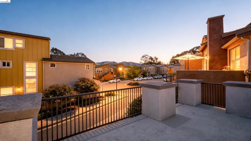 Outdoor patio featuring a concrete surface, black metal railing, and stucco-finished pillars