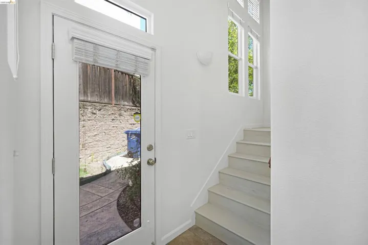 Entryway featuring a full-light door with transom window, white interior walls, and light-toned stair treads