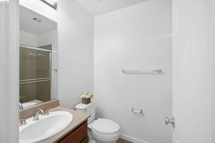Bathroom featuring a shower with sliding glass doors, a vanity with an integrated sink, a toilet, and a wall-mounted towel bar
