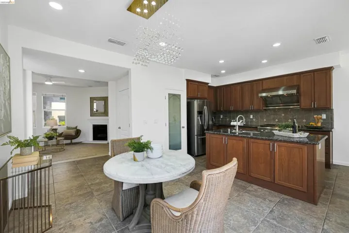 Kitchen featuring a central island with an undermount sink, dark wood cabinetry, stainless steel appliances, and a tile backsplash