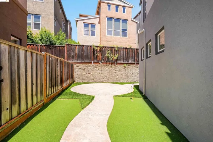 Rear yard featuring a putting green, concrete patio, and privacy fencing
