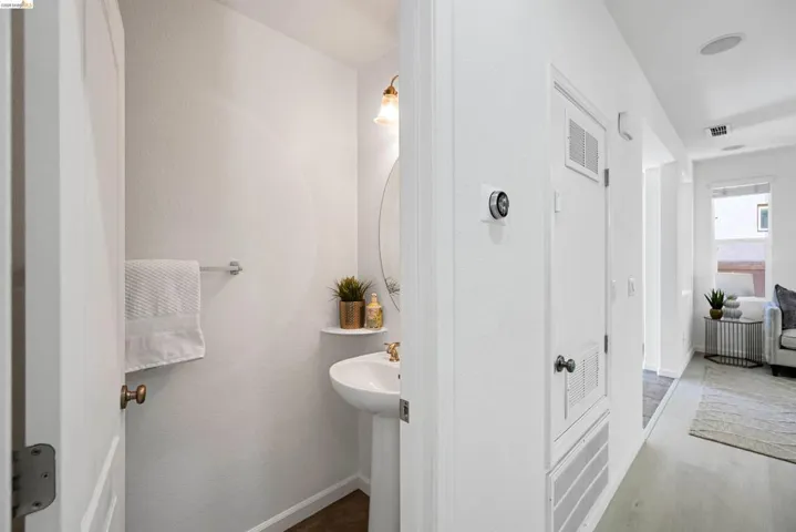 Pedestal sink with brass-toned hardware, an oval mirror, and an overhead vanity light