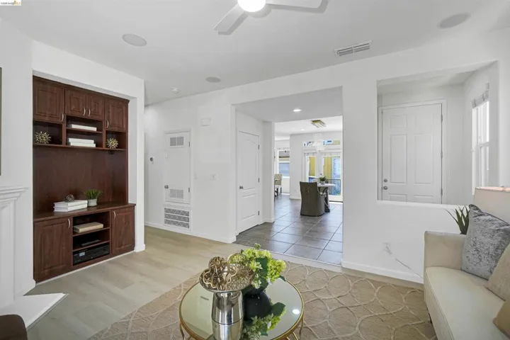 Living area featuring wood-finish flooring, a built-in entertainment center, and a ceiling fan