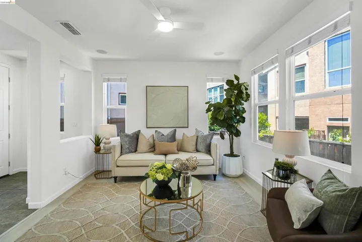 Living area featuring light wood-finish flooring, white walls, and multiple windows with roller shades