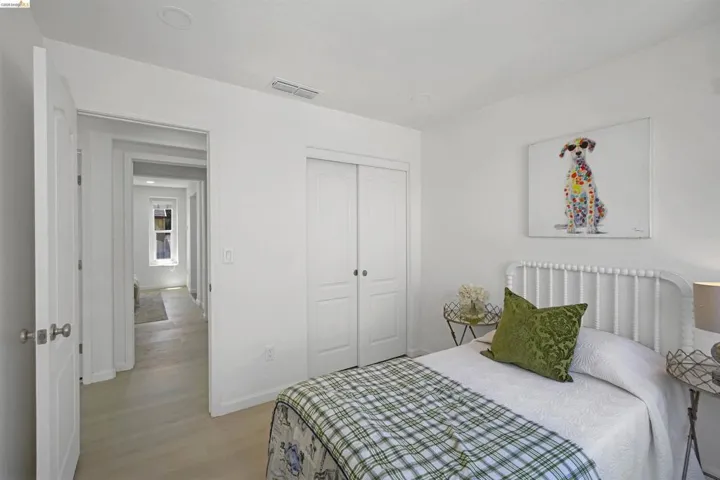 Light-filled interior featuring white walls, a white paneled door, and wood-finish flooring