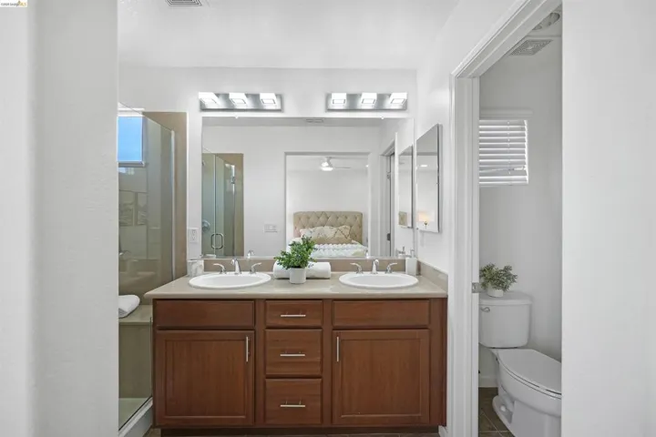 Double vanity with wood-finish cabinetry, integrated sinks, and polished chrome fixtures