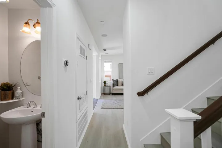 Hallway featuring wood-finish flooring, recessed lighting, and a staircase with a dark wood handrail and white newel post