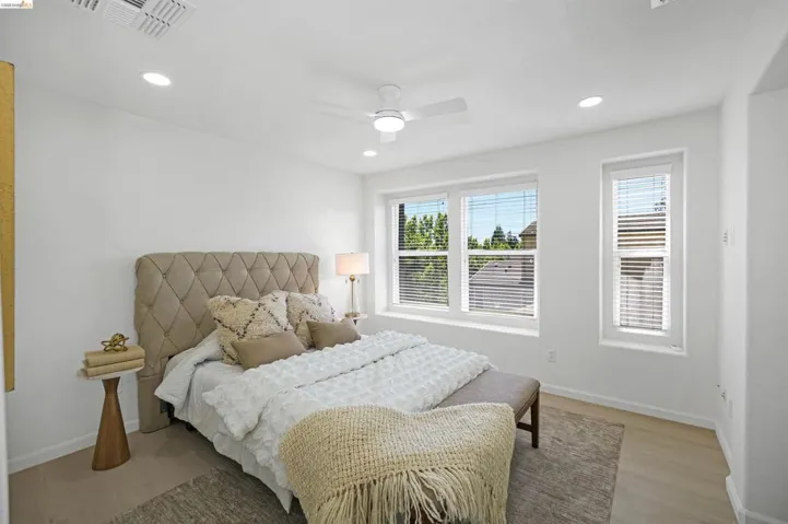 Bright bedroom featuring multiple windows with blinds, recessed lighting, a ceiling fan, and light wood-finish flooring