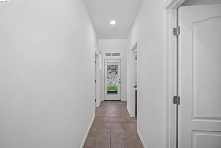 Hallway featuring tile flooring, white walls, and recessed lighting