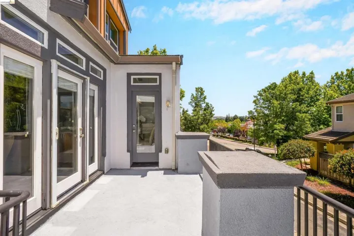 Spacious outdoor deck featuring multiple glass-paned doors and a contemporary metal railing