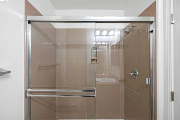 Enclosed shower with sliding glass doors and chrome hardware