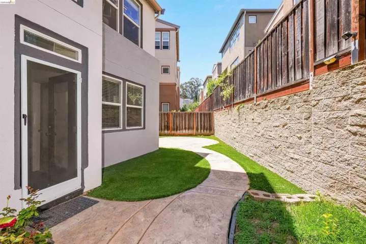 Curved concrete pathway with artificial turf landscaping leading to a private entrance