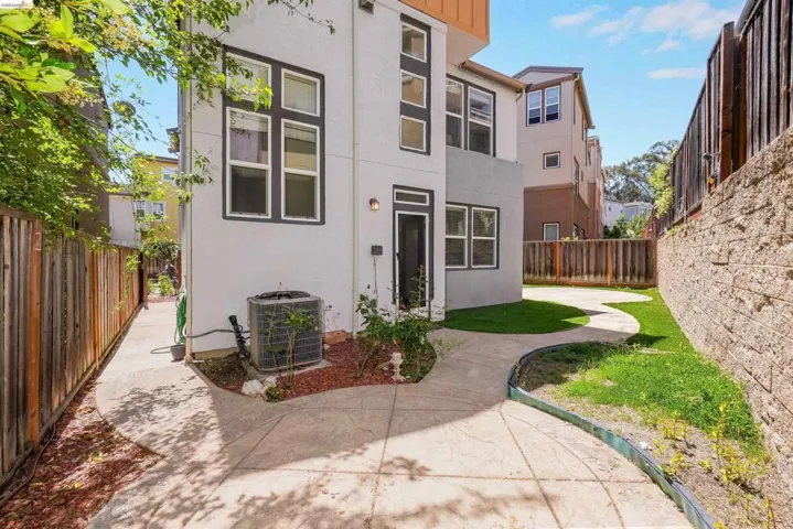 Rear exterior featuring a white stucco finish, dark framed windows, and a concrete patio