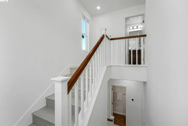 Staircase featuring white risers, light-toned treads, and a banister with white balusters and a wood-finish handrail