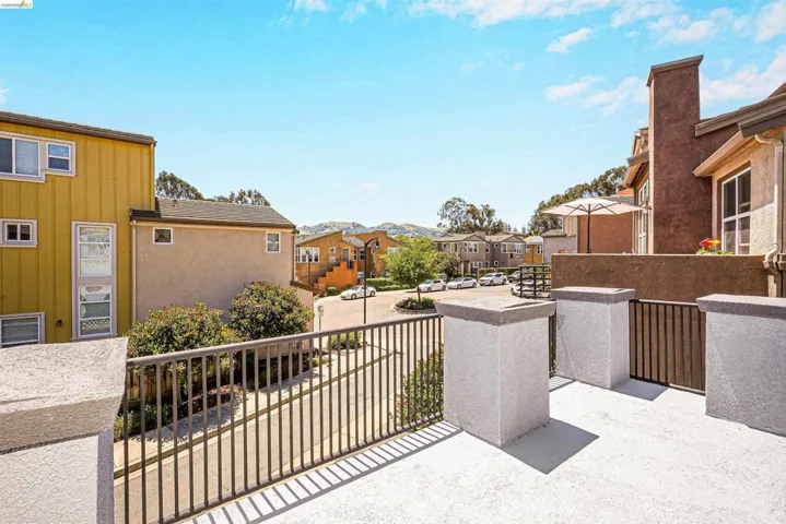 Exterior balcony featuring a concrete surface, black metal railings, and stucco pillars