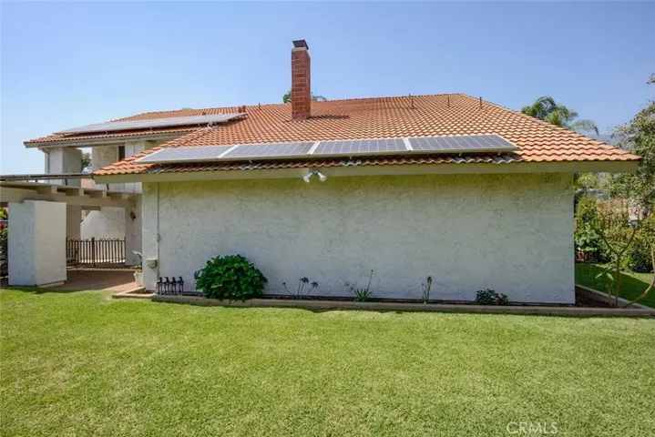 View from side yard showing money saving seller owned solar panels on tile roof